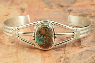 Genuine Royston Turquoise set in Sterling Silver Bracelet. The Royston Turquoise Mine was originally known as the Royal Blue Mine. It produces Turquoise that has a mixture of blues and greens in the same formation. The Royston Turquoise Mine is located in Nye County, Nevada. Created by Navajo Artist Arkie Nelson. Signed by the artist.